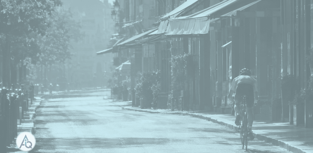 Fietser op een lege, zinderende straat met uitgerolde zonneschermen tijdens de heetste middag van het jaar