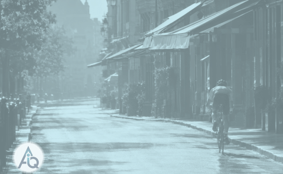 Fietser op een lege, zinderende straat met uitgerolde zonneschermen tijdens de heetste middag van het jaar