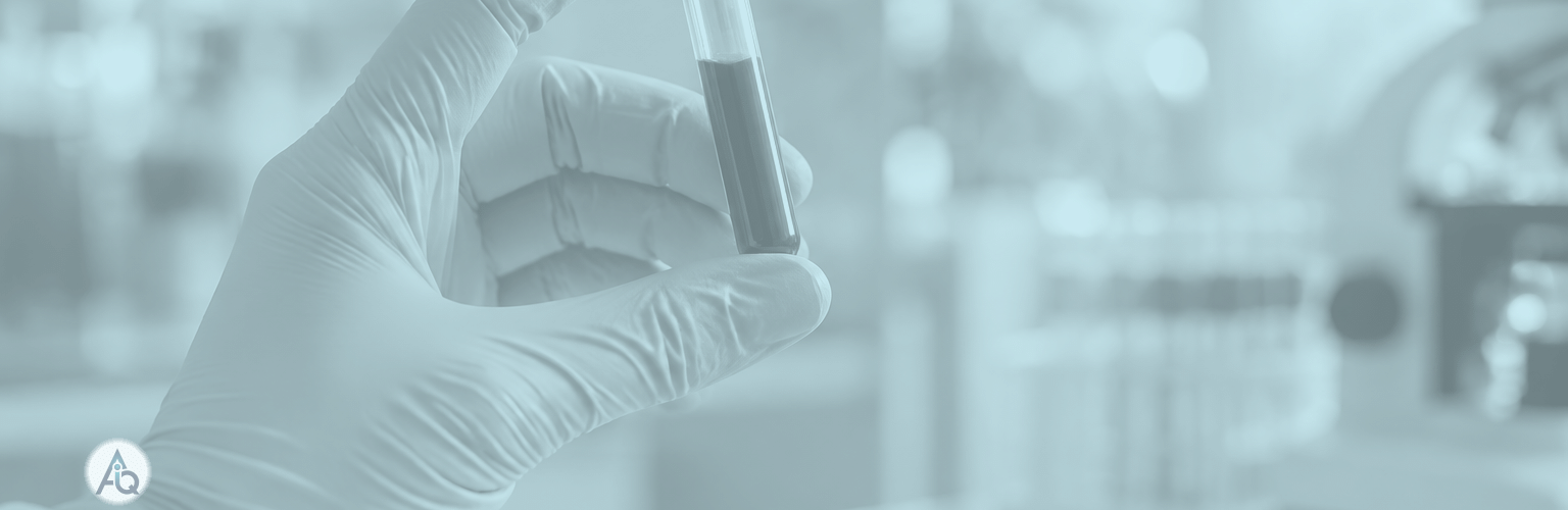 Een glazen bloedbuisje wordt tegen zacht ochtendlicht in een laboratorium gehouden met een groenblauw vervaagde achtergrond