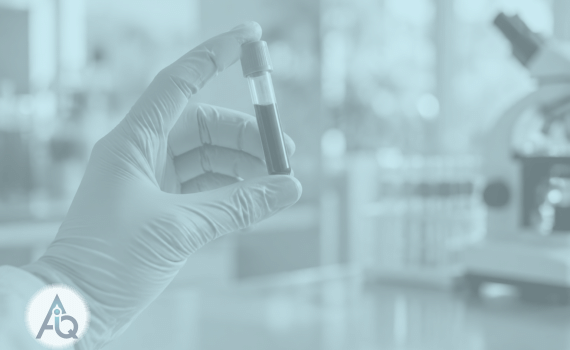 Een glazen bloedbuisje wordt tegen zacht ochtendlicht in een laboratorium gehouden met een groenblauw vervaagde achtergrond