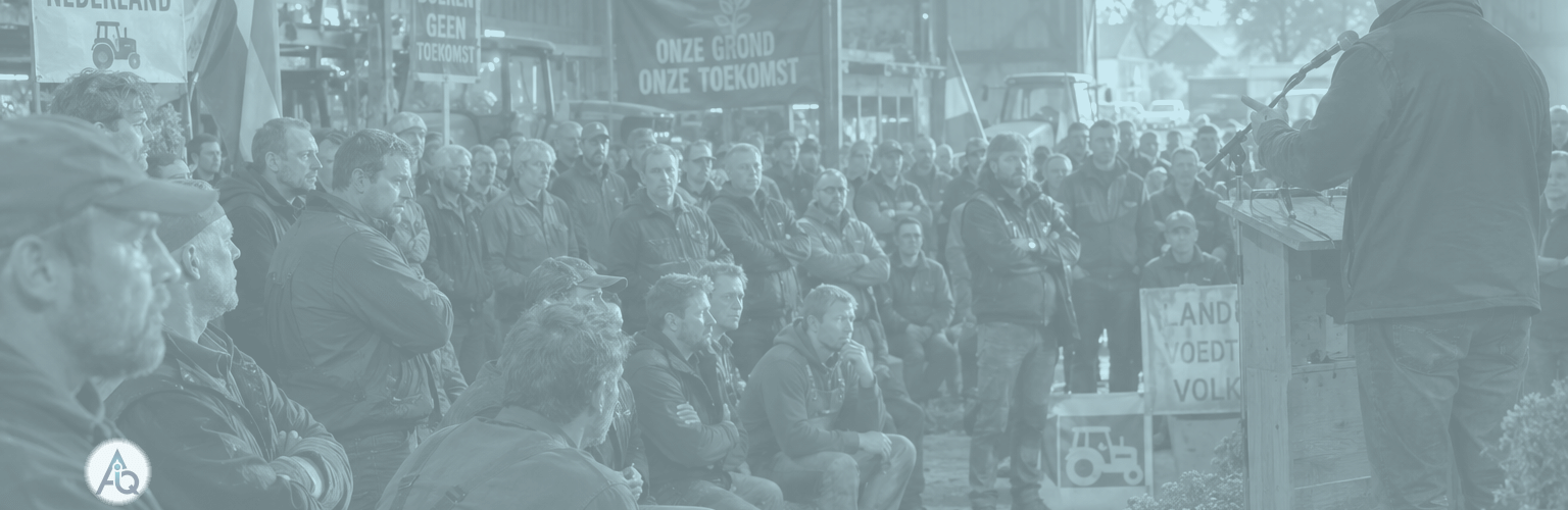 Boeren luisteren tijdens een bijeenkomst in een schuur naar een spreker over het stikstofbeleid