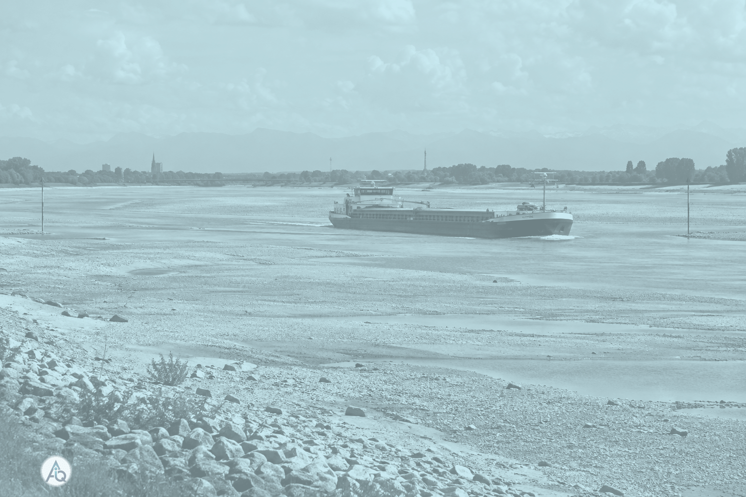 Vrachtschip op de Rijn bij extreem laagwater, met drooggevallen rivierbodem en de Alpen in de verte